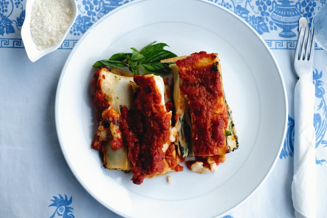 a white plate topped with lasagna covered in sauce